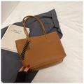 Detail view of brown pebbled leather tote with fashion embossing and tennis racket charm - Brown