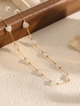 Gold chain necklace with iridescent white heart beads displayed on a wooden tray - Gold+White