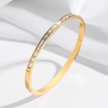 Gold oval bangle with channel-set rectangular zircon stones on a white background - Gold