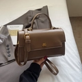 Brown faux leather crossbody bag with top handle and gold logo in a stylish setting - Khaki