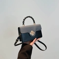 Retro two-tone handbag with gray woven flap, black leather body, and gold flower lock - Black
