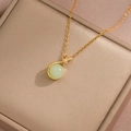 Macro della collana dorata con pendente di perla verde su un portagioie in metallo - Collana Piccola Verde Sacchetto Portafortuna