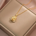 Dettaglio della collana a camelia dorata con zirconi incastonati su una scatola da regalo - Collana con Fiore Rotante Oro (X1033)