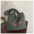 Detail einer großen dunkelgrünen Nylon-Tragetasche mit orangefarbenem Text auf Holz - Dunkelgrün