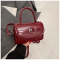 Elegant burgundy patent leather handbag with top handle and crossbody strap on blazer - Red