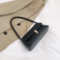 Detail einer minimalistischen schwarzen Leder-Baguette-Tasche mit goldenem Metallverschluss - Schwarz