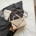 Beige leather crossbody bag with sparkling gold sequins and woven handle in lifestyle setting - Khaki
