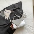 Silver square handbag with glitter triangle design and twist handle displayed on a blazer - Silver