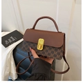 Close-up of contrast letter print bag with gold metal twist lock and brown handle - Brown