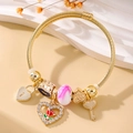 Detailed macro of a gold cable bracelet with romantic heart and rose charms on a stone base - Gold Style 008