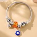 Detail of silver twisted bracelet with orange bead, heart charms and evil eye pendant - Silver Style 002