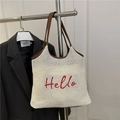 White woven straw tote bag with red Hello embroidery and brown leather trim accents - White
