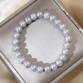 Detailed view of grey pearls bracelet with high luster on gold satin fabric background - Gray