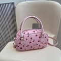 Borsa a cilindro rosa con stampa di ciliegie e tracolla staccabile su una sedia - Rosa