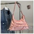 Détail d'un sac à bandoulière plissé rose clair avec nœuds et logo mode texturé - Rose