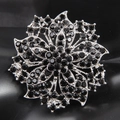 Detailed close-up of a silver flower brooch with pave-set black rhinestones - Black