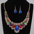 Luxurious gold jewelry set with colorful gemstones and large blue pendant on a model - Colorful