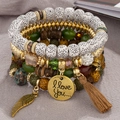 Dettaglio di braccialetti di perline boho a strati con ciondolo ala e nappa marrone - Verde Sfumato