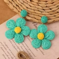 Close-up of handmade green and yellow raffia petal earrings on a vintage paper background - Green