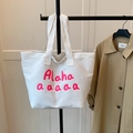 White canvas tote bag with red letter print on hanger with trench coat background - White
