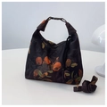Détail du sac croissant fleuri avec motif orange et bandoulière réglable sur bureau - Bonne Chance/Tout Va Bien