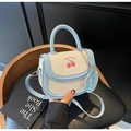 Detail of light blue saddle bag with cherry pattern and donut charm on black leather seat - Blue