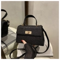 Detalle de bolso negro de lentejuelas con cierre dorado sobre una silla blanca - Negro