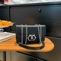 Borsa a tracolla in pelle nera con catena argento e chiusura logo su tavolo di legno - Nero