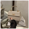 Detailed macro view of champagne gold sequined handbag featuring a golden swivel lock - Gold