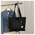 Dettaglio borsa tote in nylon nero con tasca frontale a zip e toppa Good Luck - Nero
