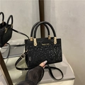 Elegante borsa nera con trama geometrica a serpente e finiture dorate - Nero