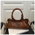Detailed close-up of brown punk handbag with metal cross pendant and rivet studs - Brown