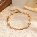 Dettaglio del bracciale dorato con margherite rosa e ciondoli a cuore su superficie ruvida - Oro-Margherita Rosa (STB2542-GO-RP)