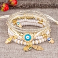 Detail of layered beaded bracelets with Evil Eye and Hamsa Hand charms and Love heart - 6-Piece Set / White