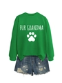 Detail van groene Fur Grandma-sweatshirt met pootafdruk en distressed denim korte broek - S / Groen (Witte Letters)