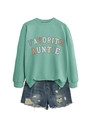 Flat lay of a mint green sweatshirt with 'FAVORITE AUNTIE' text and distressed denim shorts - Light Green