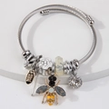 Silver woven steel bangle with bee, flower, and crystal charms on a display stand - Yellow