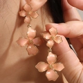 Elegante pfirsichrosa Doppelkleeblatt-Ohrringe mit Goldrand an einem Modell - Pfirsichorange