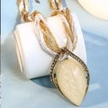 Long collier bohème avec pendentif pierre jaune sur une tasse en céramique blanche - Abricot