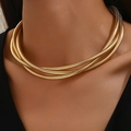 Detail einer mehrlagigen goldenen Schlangenkette als Choker am Hals eines Models - Gold