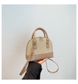 Dettaglio di una mano che tiene una borsa a tracolla in paglia con finiture in pelle - Cachi