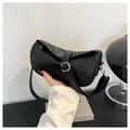 Detail of black pebbled leather crossbody bag featuring gold buckle and soft cylinder shape - Black