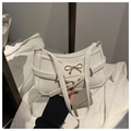 Detail of creamy white underarm bag with elegant golden bow clasp and thin shoulder strap - White