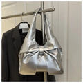 Detail of silver metallic bow-shaped handbag on a hanger with sleek modern finish - Silver