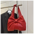 Detail of red tote bag featuring a large decorative bow and matte leather texture - Red