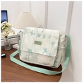 Detalle de bolso de lona crema con estampado de mariposa verde sobre mesa de madera - Verde