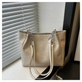 Detail of cream leather tote bag with geometric stitching and silver chain under natural light - Beige