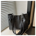 Detail of black patchwork tote bag with silver chain straps on a minimalist windowsill - Black