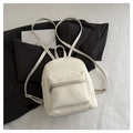 Detalle de una mini mochila minimalista blanco crema con correas ajustables y bolsillo frontal - Blanco