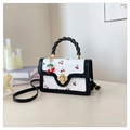 Close-up of cute cherry print handbag with golden floral twist lock and detachable charm - Black